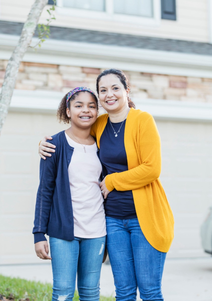 Mother and daughter smiling outside their home, the daughter wearing braces