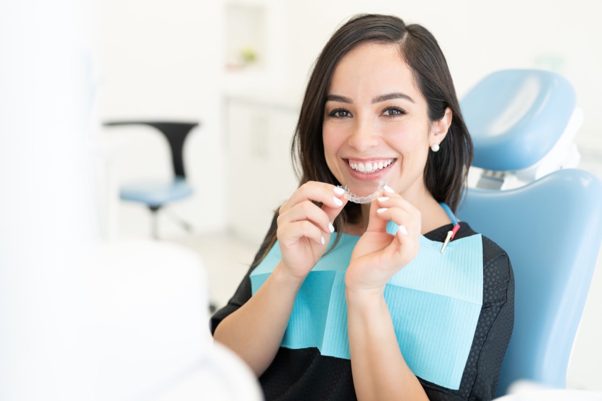 Adult patient holding a clear aligner in the treatment chair